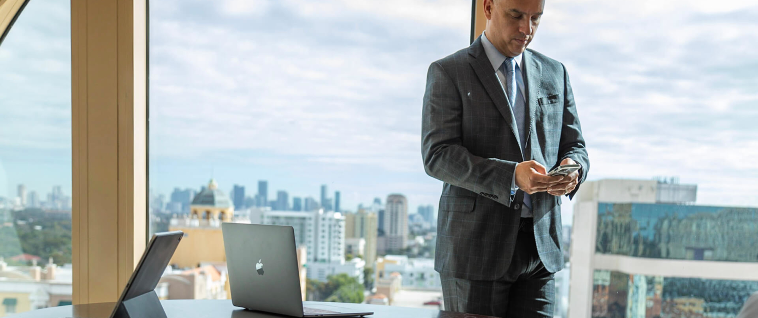 Man looking at his cellphone in front of large windows